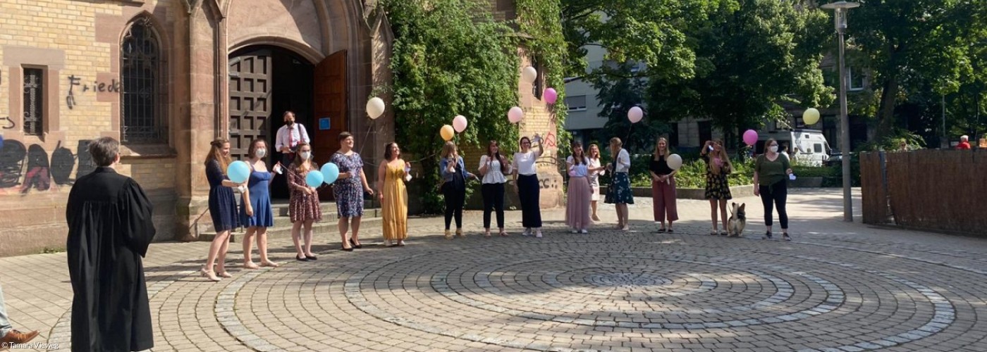 Junge Menschen mit Luftballons vor Kirche